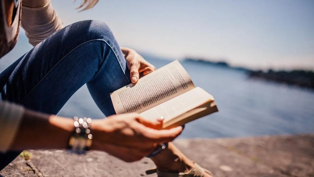 Persona leyendo un libro al mar en el D&iacute;a del Libro en Burgos